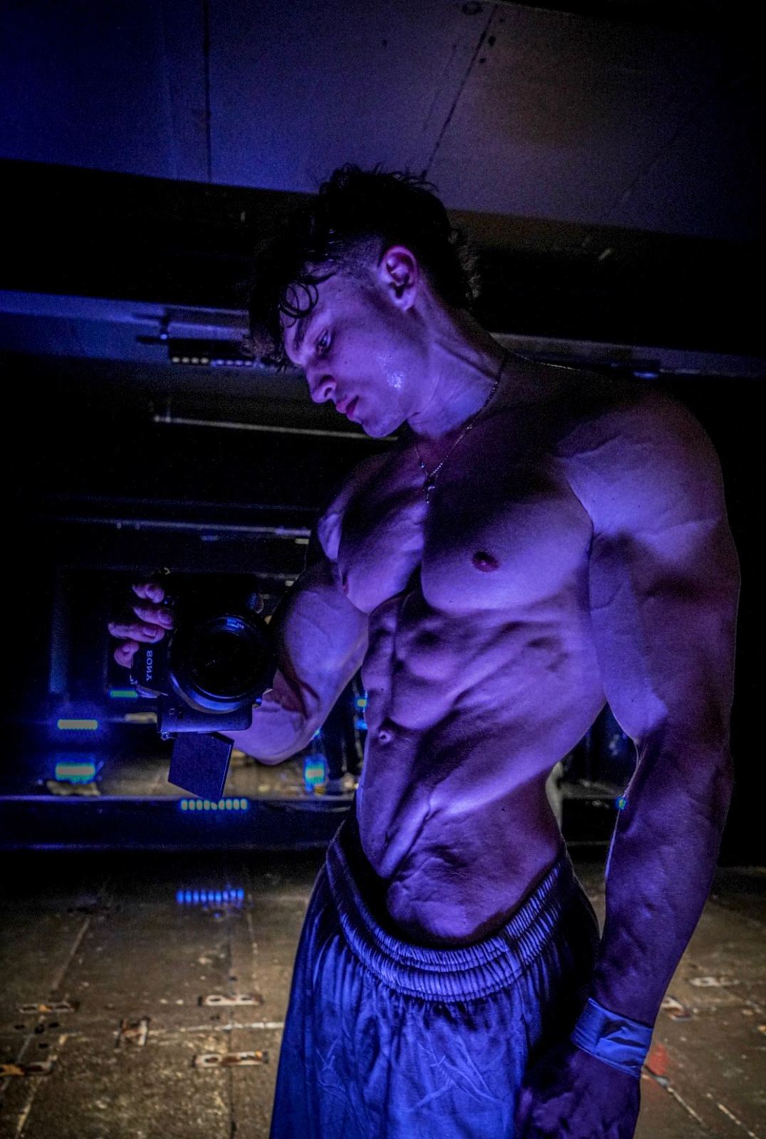 Aaron Smith flexing under purple gym light